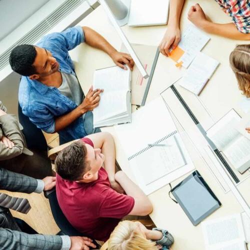 High angle view of professors and university students discussing at table in classroom